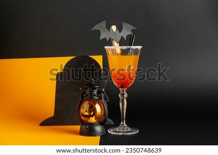 Glass of tasty Margarita cocktail for Halloween with lantern and tombstone on color background
