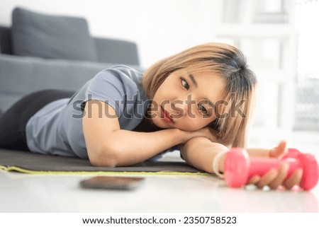 Young asian woman bored with exercise in home. Lazy asian woman exercising bored face holding dumbbells giving up fitness concept. Royalty-Free Stock Photo #2350758523