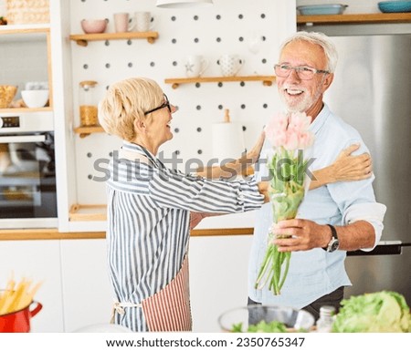 Portrait of happy senior couple with flowers  in kitchen