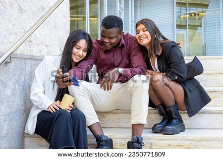 Happy coworkers taking a selfie photo at work break. Group of young student friends smiling at university outdoors. Ethnic diversity.