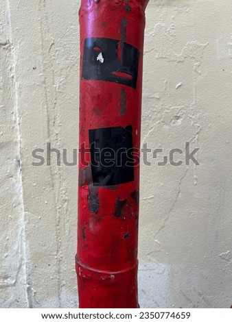 Old industrial red painted vintage wall pipe detail with torn peeled worn street stickers labels 