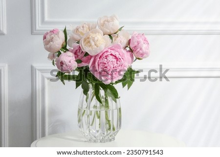 Beautiful peonies in glass vase on white table. Space for text