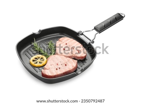 Grill pan with delicious tuna steaks, lemon and rosemary on white background