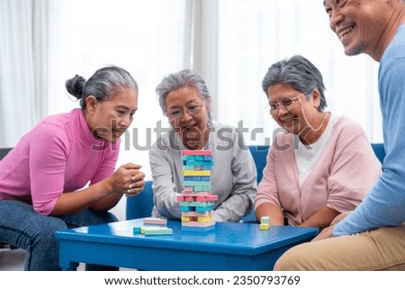 Group of senior people sitting at the table and playing board games together in nursing home