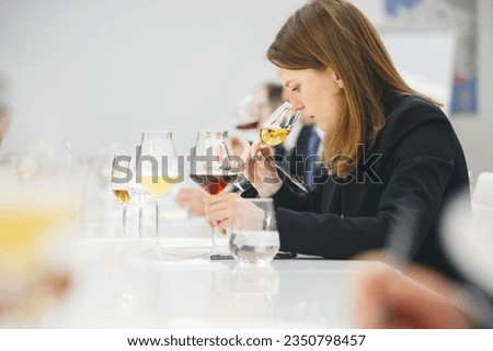 Female sommelier sniffing unknown alcoholic drink during blind tasting. Sommelier exam to study different wine and beer.  Royalty-Free Stock Photo #2350798457