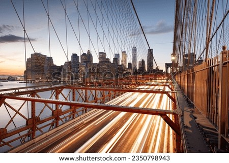 The view of the Financial District in New York City behind traffic on the Brooklyn Bridge after sunset.