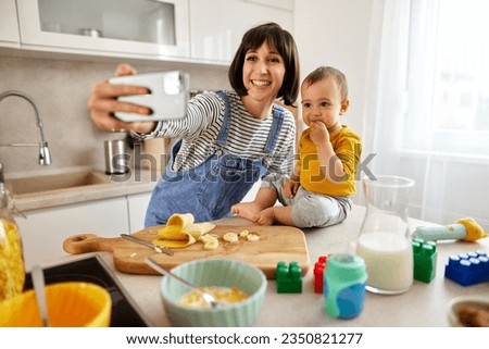 Mother taking Selfie with her baby boy in the kitchen
