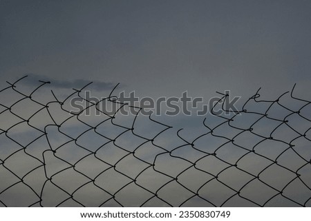 Old rusty damaged wire mesh with sky background, freedom concept, copy space. Opening in metallic fence against a blue sky with clouds. breakthrough concept. Chain-link, wire netting wire-mesh