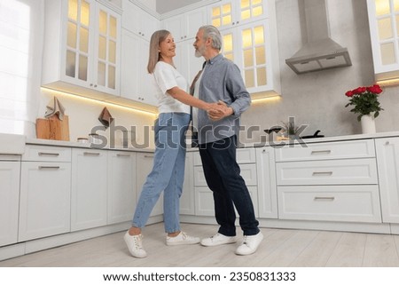 Happy affectionate senior couple dancing in kitchen, low angle view Royalty-Free Stock Photo #2350831333