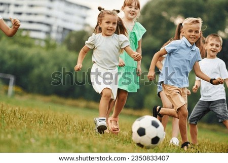 Playing soccer. Kids are having fun on the field at daytime together.