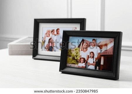 Framed family photos on white wooden table indoors. Space for text