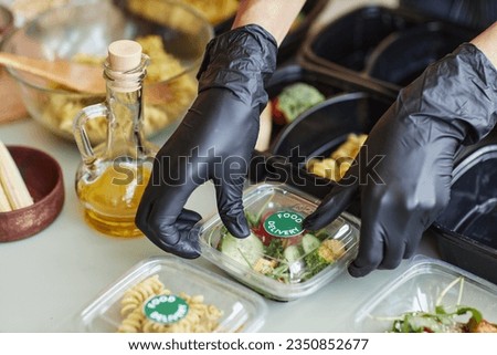 Close up of cafe worker wearing gloves packing food delivery order with salad, copy space Royalty-Free Stock Photo #2350852677