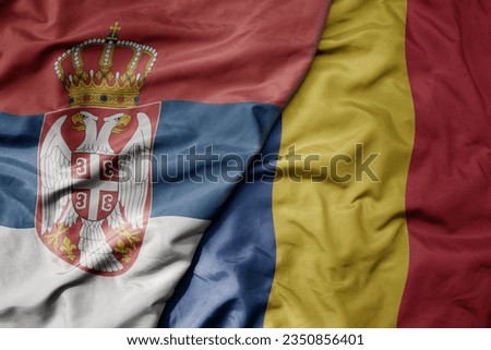 big waving national colorful flag of serbia and national flag of romania . macro