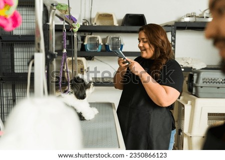 Woman worker taking pictures with her phone for social media of a shih tzu dog at the grooming shop spa