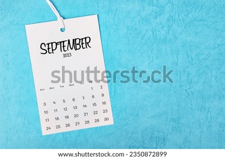 2023 September calendar page hanged on white rope  on blue background.