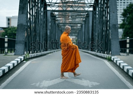 Buddhist monks are morning walking on routes between rural villages on the ancient iron bridge the travel destination of Chiang Mai, Thailand. Concepts make merit with monks in culture and religion. Royalty-Free Stock Photo #2350883135