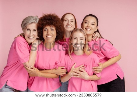 Group of smiling confident multiracial women wearing t shirts with pink ribbon looking at camera isolated on pink background. Health care, support, prevention. Breast cancer awareness month concept Royalty-Free Stock Photo #2350885579