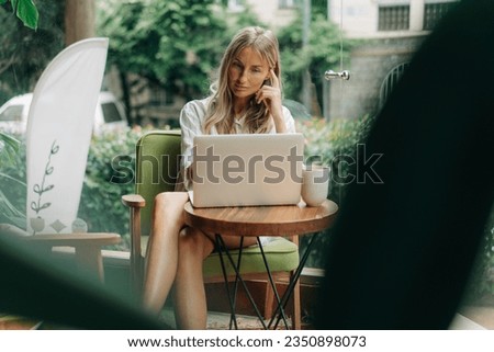 Remote working woman typing on a laptop while sitting in a coffee shop. Royalty-Free Stock Photo #2350898073