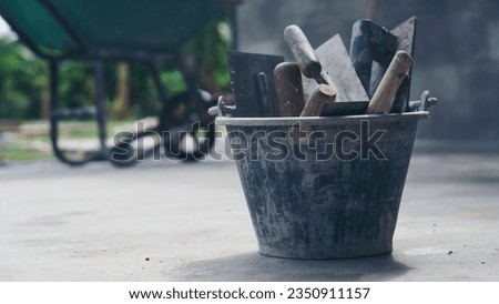 Powder Cement and sand mixing bucket tank, trowel, and plastering equipment in construction site.  Royalty-Free Stock Photo #2350911157