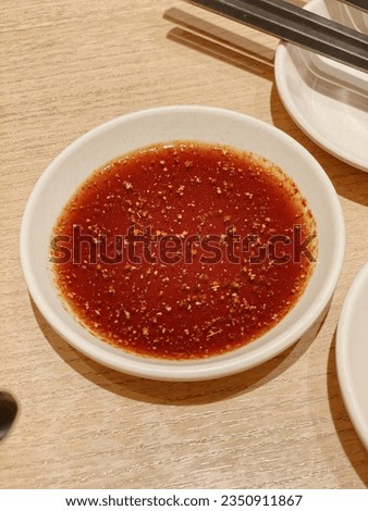 It's a picture of hot sauce, chili powder, chocolate background, small white plate