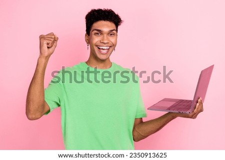 Photo of lucky excited man dressed green t-shirt rising fist winning game modern device isolated pink color background
