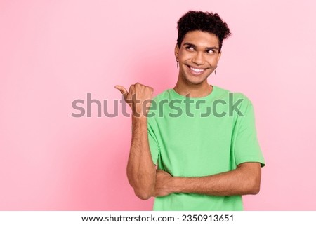 Photo of funny thoughtful man dressed green t-shirt showing thumb looking empty space isolated pink color background