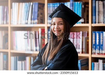 Portrait young happy and excited Asian woman university graduate in graduation gown and cap in the library. Education stock photo