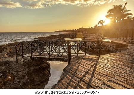 Sunset at sunset of a wooden pier set among the rocks on the coast of Puerto Aventuras in Mexico.