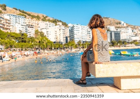 Woman tourist on vacation sitting by the sea at Saranda Beach on the Albanian Riviera in Sarande, Albania