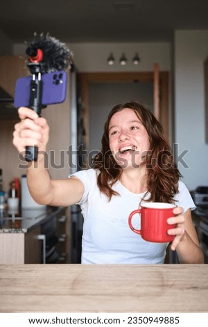 Cheerful woman using phone to livestreaming at home