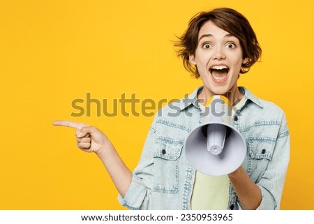 Young happy woman she wear green t-shirt denim shirt casual clothes hold in hand megaphone scream announces discounts sale Hurry up point aside isolated on plain yellow background. Lifestyle concept Royalty-Free Stock Photo #2350953965