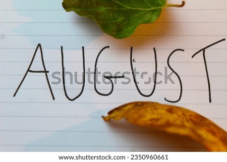 A photo of the month August written on a white page surrounded by leaves. 