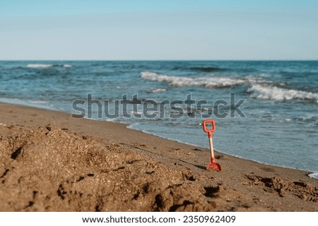 children's shovel sticks out in the sand on the seashore on the 