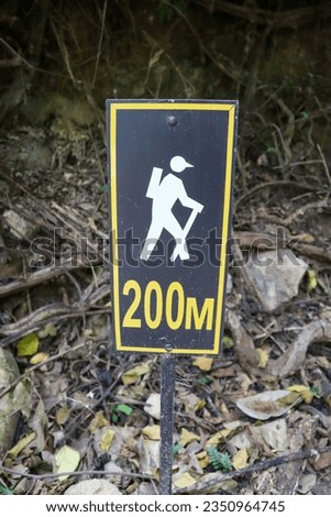 A sign showing a man walking up the hill for another 200 meters to the destination.