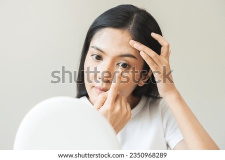 Ophthalmology care, eye sight, vision concept. Asian young woman, female hand holding and putting, wearing soft contact lenses with finger on face, girl looking in mirror at home. Medicine and health. Royalty-Free Stock Photo #2350968289