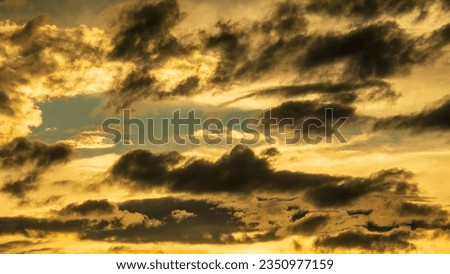 Clouds in silhouette and others in sunlight in a crowded sky at sunset in springtime, southwest Florida. For motifs of change, transition, and yin and yang.