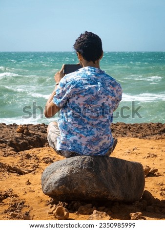 Young Latin Man Taking a Picture with his Phone of the Sea in the Desert in Uribia, La Guajira, Colombia