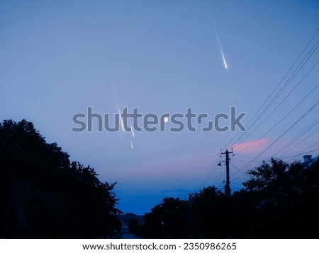 Meteorites in a clear sky at dusk. Bright meteors over the evening village. Astrophotography of shooting stars.