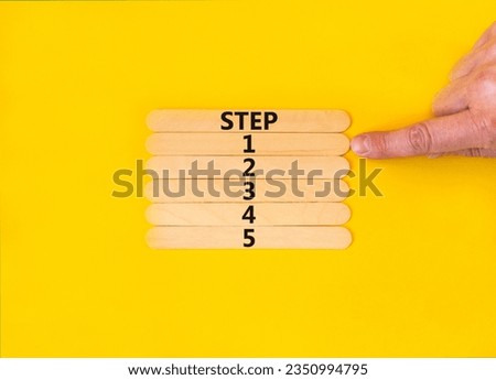 Time to step 1 symbol. Concept word Step 1 2 3 4 5 on wooden sticks. Businessman hand. Beautiful yellow table yellow background. Business planning and time to step 1 concept. Copy space.