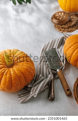 Whole pumpkins on the table. A sunny day. Decorated with textiles and kitchen equipment. Autumn harvest