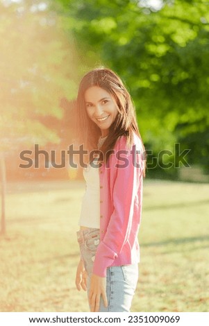 Portrait of attractive smiling woman with beautiful hair looking at camera on the street. Happy model posing for picture outdoors. Breast cancer awareness month concept