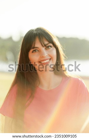 Portrait of attractive smiling woman with beautiful hair looking at camera on the street. Happy model posing for picture outdoors. Breast cancer awareness month concept