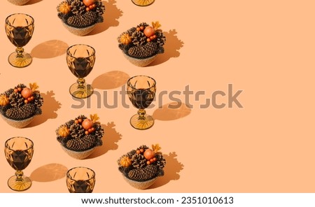 Creative autumn pattern made with fallen leaves, berries, pumpkins, pinecones and glasses of red wine on pastel orange background. Minimal nature seasonal concept. Flat lay idea. Autumn aesthetic.