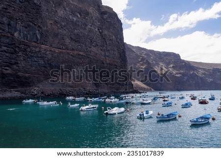 Scenic view on the small port of Vueltas seen from Playa de Vueltas in Valle Gran Rey on La Gomera, Canary Islands, Spain, Europe. Small boats are floating in the blue lagoon bay surrounded by cliffs