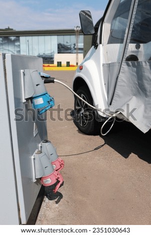 Process of charging an electric car in megalopolis. Electric car is charging. Power source for charging station of hybrid electric vehicles.Concept of an eco-friendly card. Vertical photo.