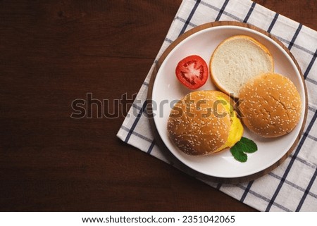 Top view of homemade cheese burger in white plate on wooden table.