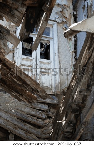 Vertical photo. View from hole in wooden floor. Broken old house. White door. Concept of poor housing, dilapidated apartment, repair, earthquake, flood, destruction, buying house, renting a property Royalty-Free Stock Photo #2351061087