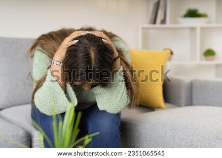 Horizontal portrait of a desperate woman looking down on the sofa