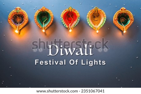 Happy Diwali - Clay Diya lamps lit during Diwali, Hindu festival of lights celebration. Colorful traditional oil lamp diya on dark background.