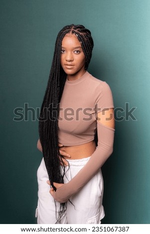 Portrait of young, beautiful black model with long braided hair. Isolated on dark cyan background. Royalty-Free Stock Photo #2351067387
